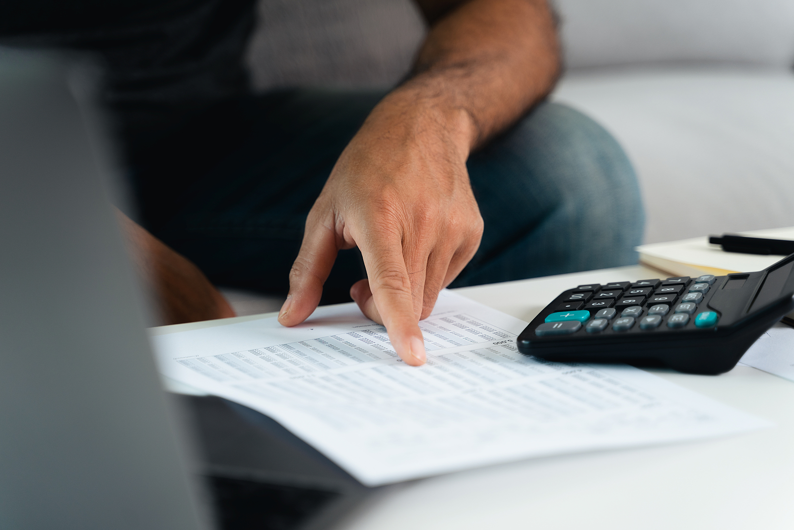 Person looking over bank statements with calculator to manage personal finances