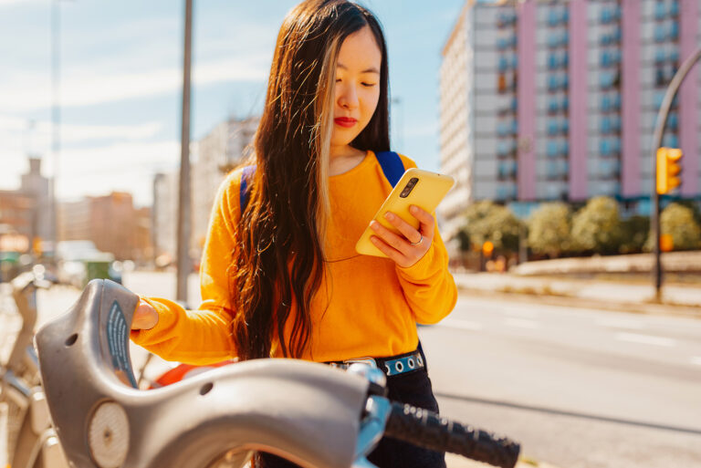 Young lady reporting rent payments to credit bureaus on her phone to rebuild credit