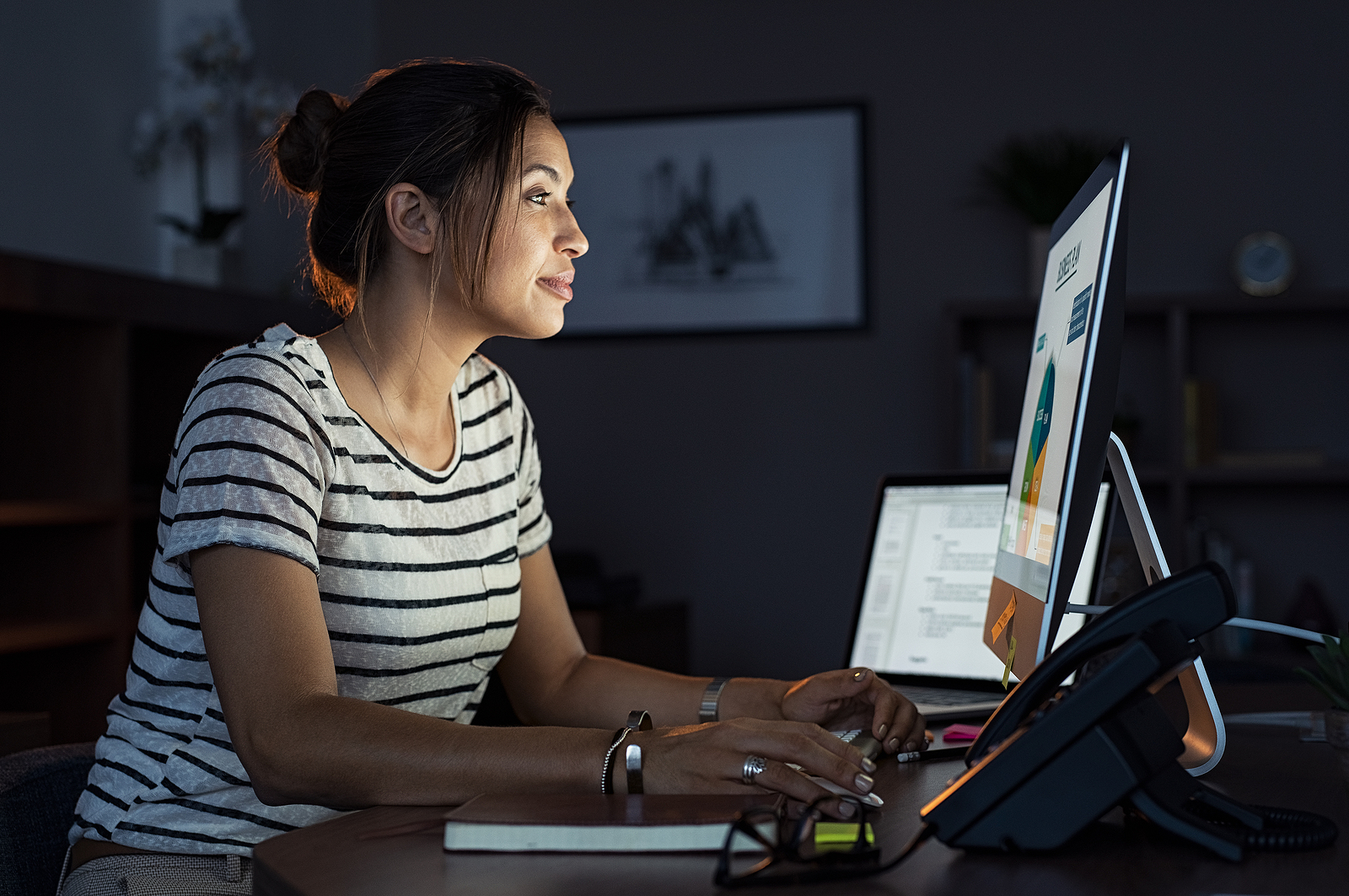 Young businesswoman in casual clothing working on desktop computer learning how to negotiate collections on your credit report. Beautiful tired business woman working on assignment at night. Girl using computer late at night in office.