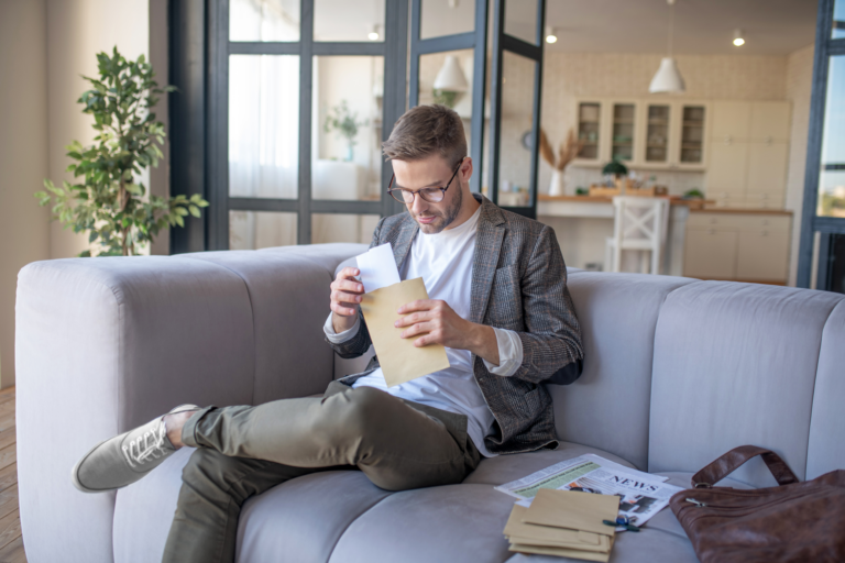 Young man in eyeglasses with an envelope in hands after finding out what is a goodwill letter