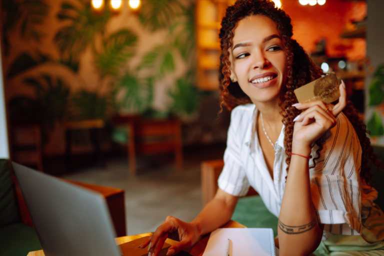 Young woman sitting at cafe How to Lower Your Credit Card Interest Rate making online shopping, using credit card and laptop. Online shopping