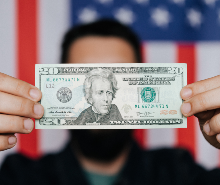 Person holding U.S. cash in front of an American flag, symbolizing how to pay down debt with your tax refund