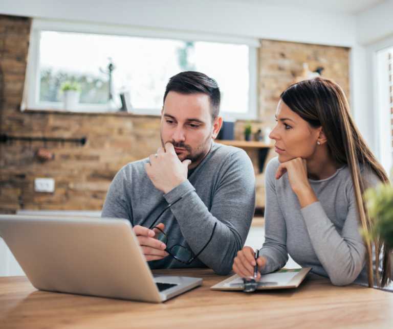 Couple reviewing their credit report together on a laptop during a mid-year credit checkup