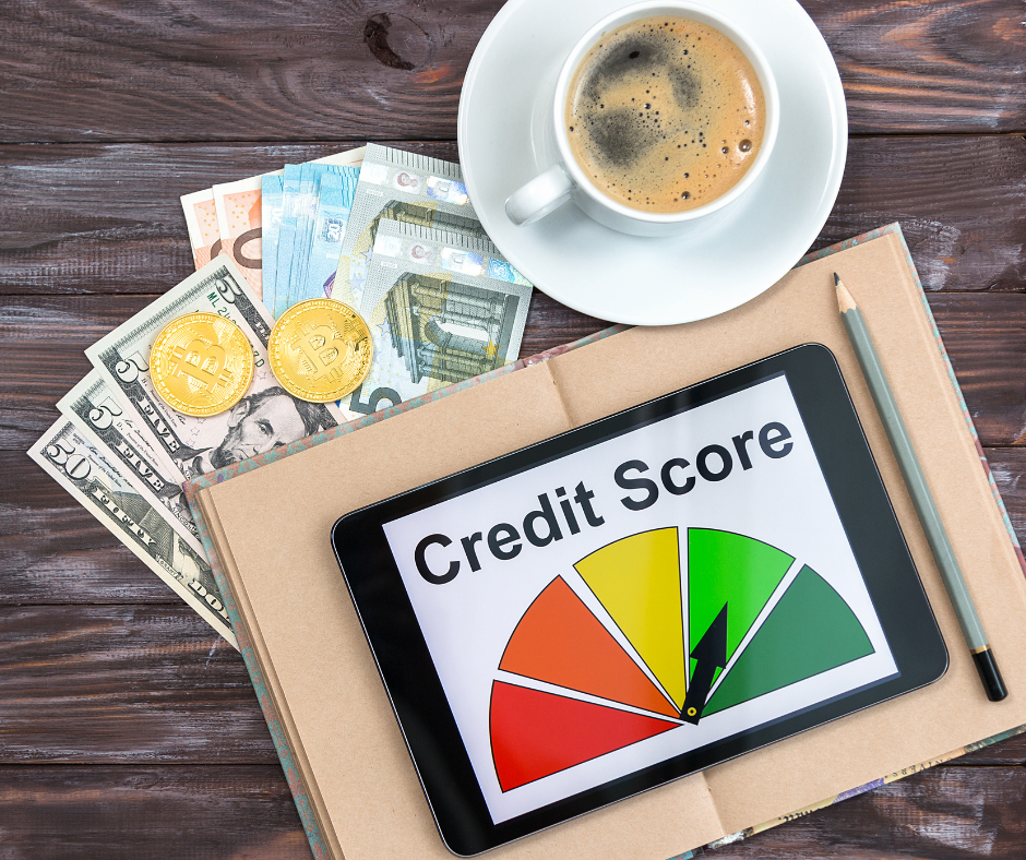 A tablet displaying a credit score gauge with a needle pointing toward good, surrounded by cash, bitcoin coins, a pencil, and a cup of coffee on a wooden desk.